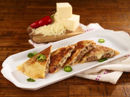 Golden-brown cheese quesadillas plated on white dish with fresh jalapeño and cilantro garnish, ideal for foodservice and wholesale food distribution.