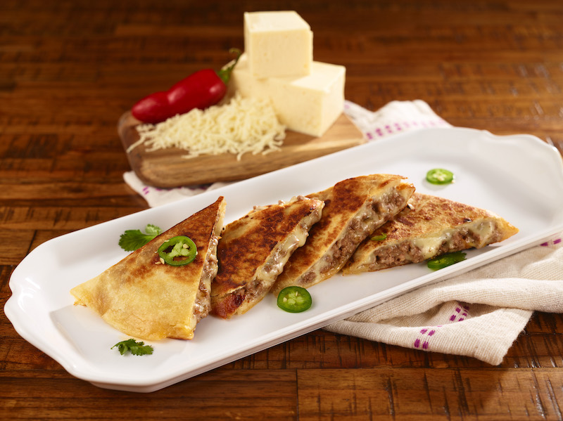 Golden-brown cheese quesadillas plated on white dish with fresh jalapeño and cilantro garnish, ideal for foodservice and wholesale food distribution.