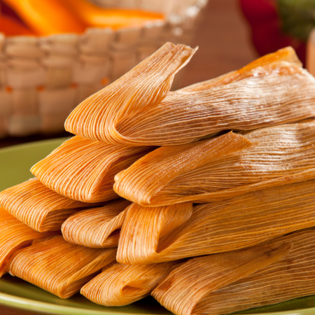 Delicious tamales stacked in vibrant corn husks, showcasing Mexican culinary tradition and warmth.